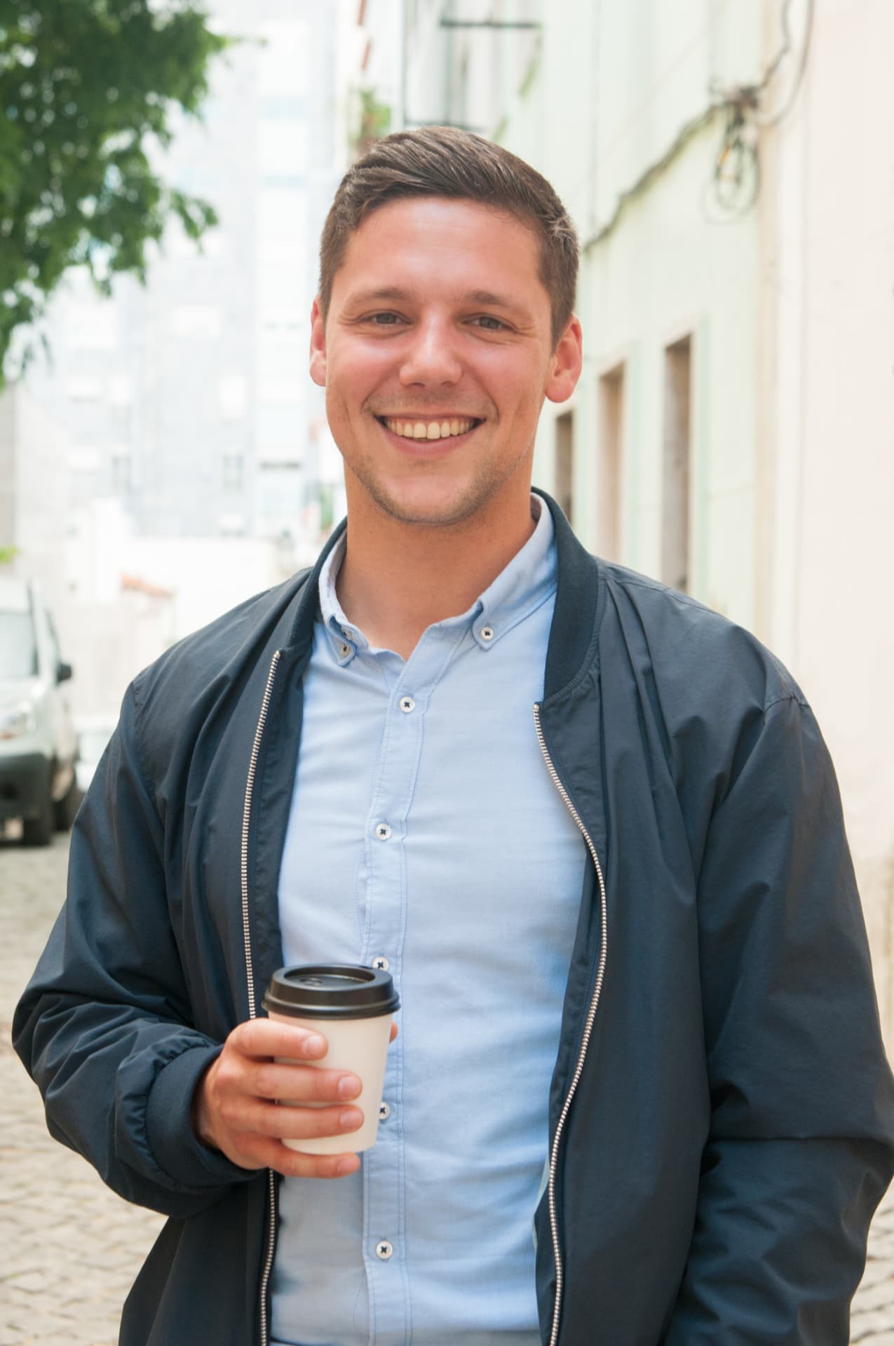 A young man smiling during an outdoor coffee break